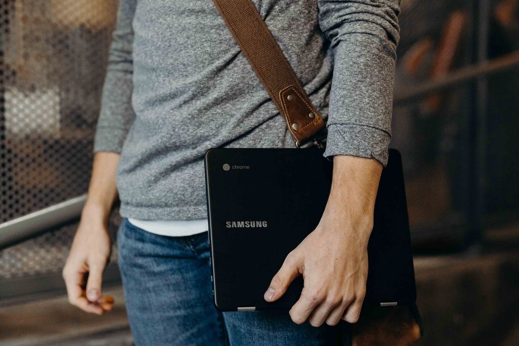 gentleman with a shoulder bag carrying a Samsung Chromebook