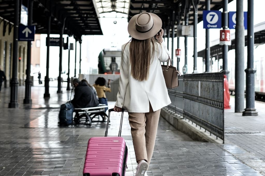 image of a woman wheeling a pink suitcase