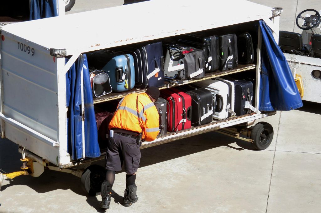 airport baggage handler loading bags onto a baggage cart