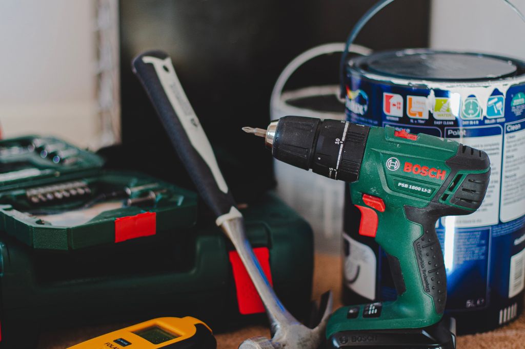 image of a Bosch power impact driver, hammer and tin of paint