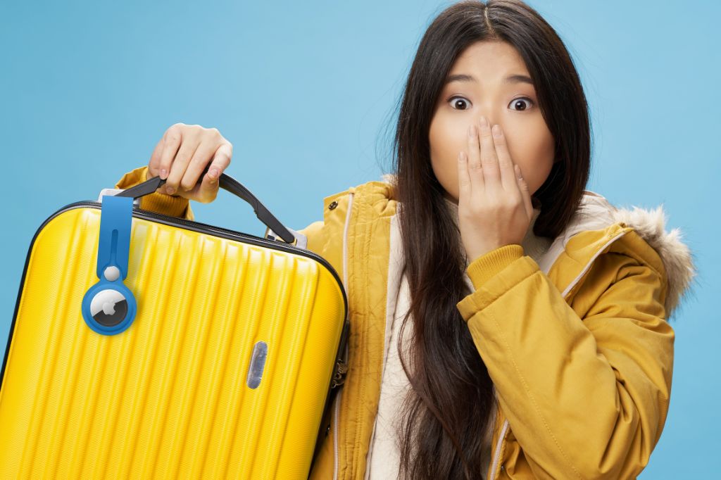 image of a woman holding a yellow suitcase with an AirTag in a blue AirTag Loop attached to the handle